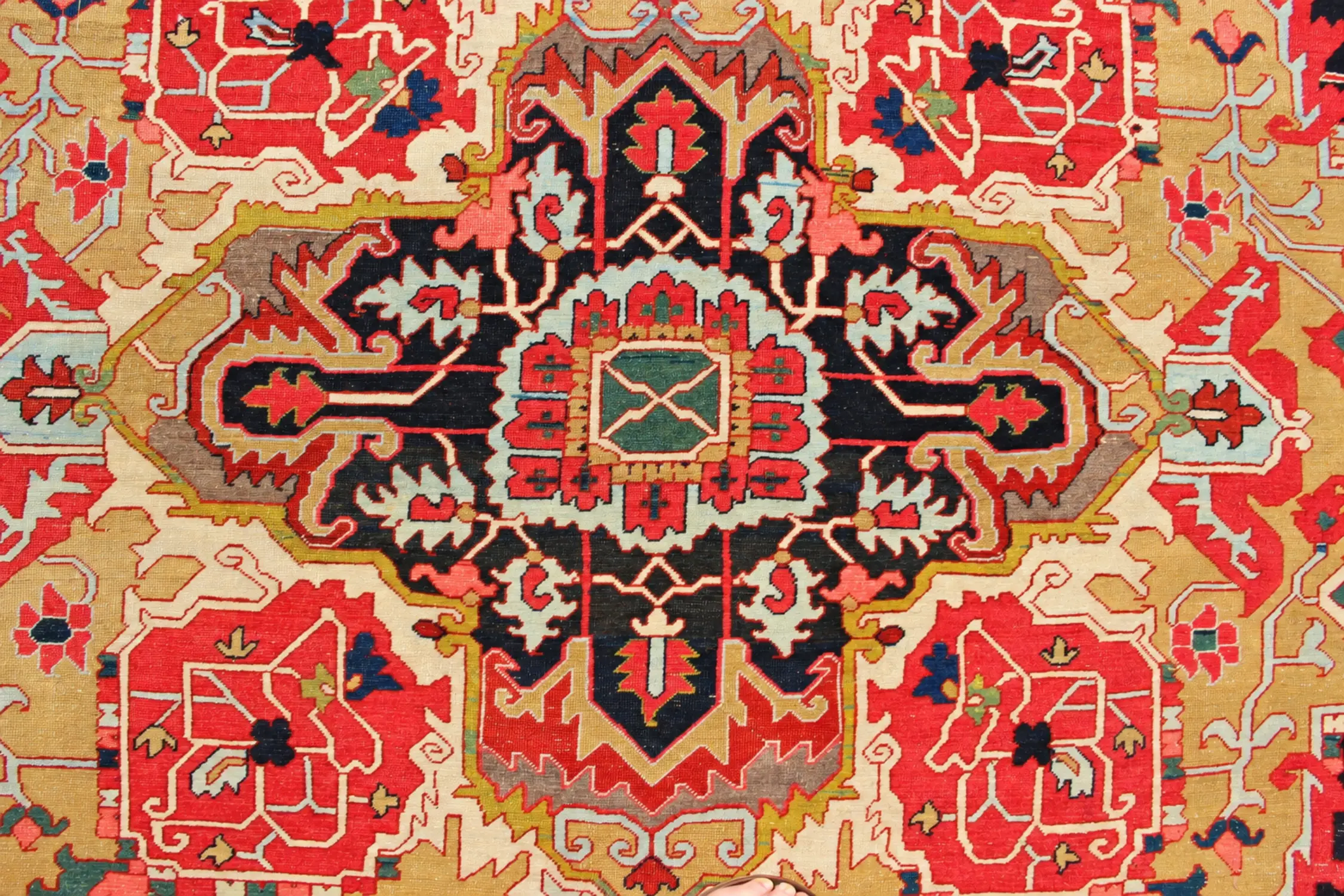 Detail of an antique carpet with a dark-blue central medallion on a red and gold field
